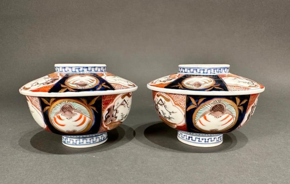 Pair of Chinese Covered Bowls: Pair of Chinese Covered Bowls, probably early 20th century in date, emulate Japanese Imari porcelains with a palette of blue, red and gold. Painted motifs of flowering plum branches and bats, symbolic