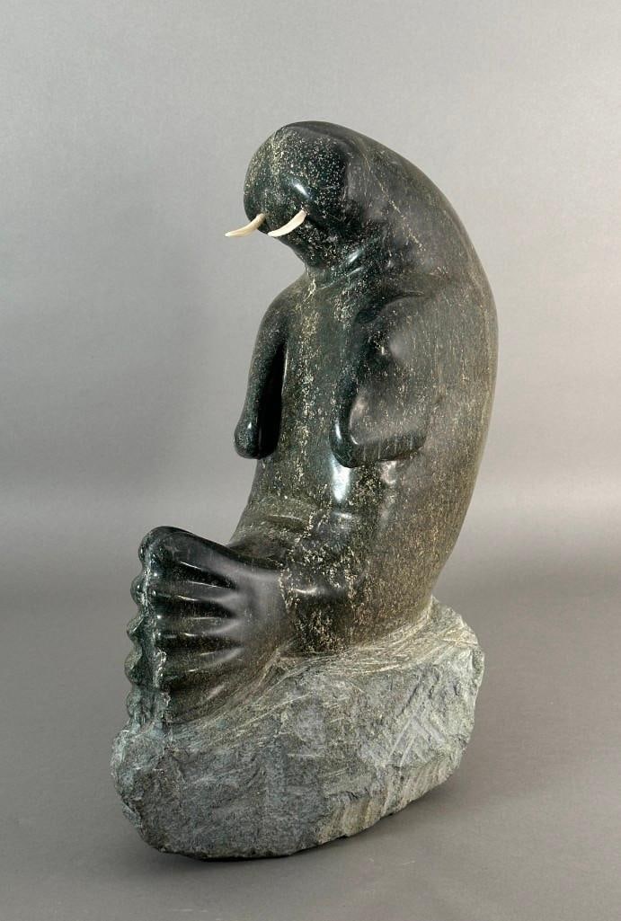 Large Inuit Carved Hardstone Figure of a Walrus: Charming Large Inuit Carved Hardstone Figure of a Walrus, seated, on a large rough carved rock, with bone tusks, no signature viewed. Dimensions: 17.5 x 14 x 8 in. Condition: One tusk loose in fitting