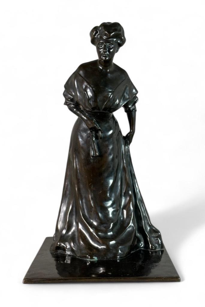Bronze of a 19th Woman Holding Glove: Hollow cast bronze with black color patina, of a 19th century mature woman in a dress, holding a glove and leaning forward with intent, on platform base. The back corner is stamped Ed. Paul Fiedler, u