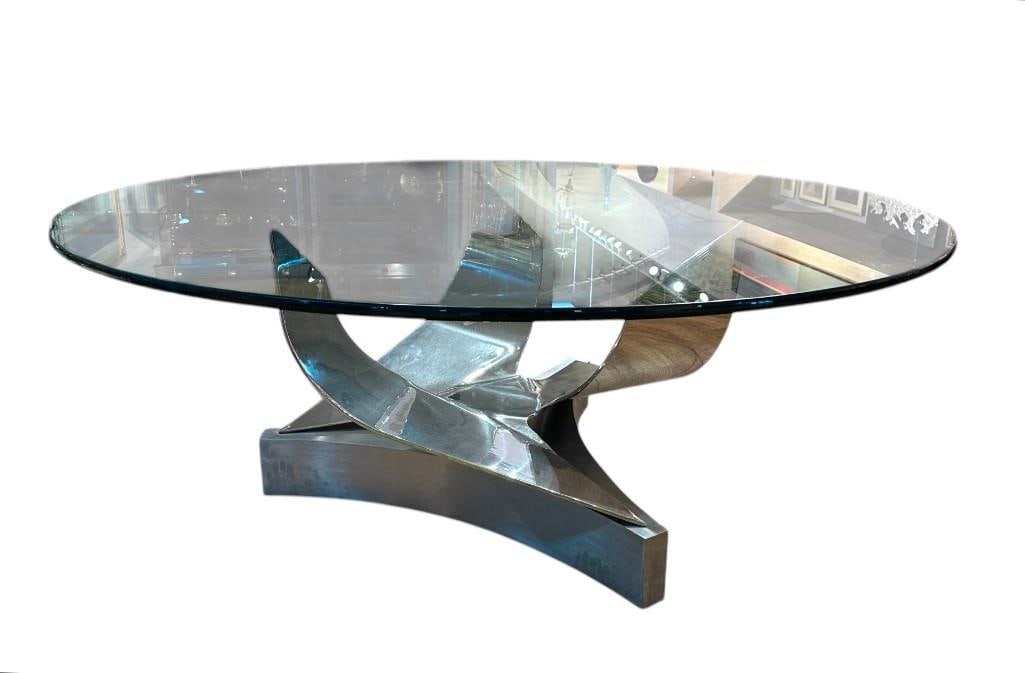 Ron Seff Coronet Polished Chrome Table with Glass Top: Ron Seff Coronet Polished Chrome Table with Glass Top, circular glass top resting on a tripart curved base. Dimensions: 29 in.h. x 72 in. dia. Condition: Very good. There is a 30 in. shallowish scratc