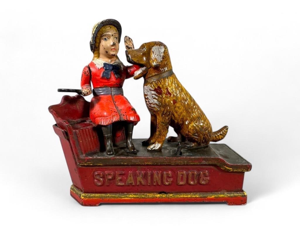 Speaking Dog Cast Iron Mechanical Bank: Speaking Dog Cast Iron Mechanical Bank, seated girl in red dress with her yellow dog, she teaching him to bark on command, the paddle in her hand drops the coin into the vault as the dog wags his tail