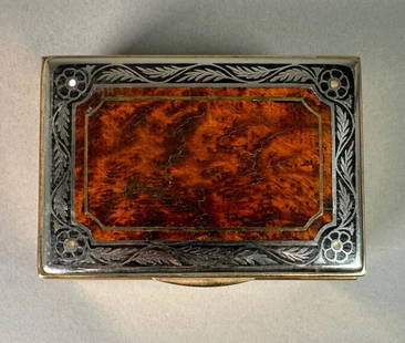 Burlwood and Silvered Metal Inlaid Cigarette Box: Burlwood and Silvered Metal Inlaid Cigarette Box, rectangular top with burl wood center, with silvered floral and leaf design over gold toned metal. Dimensions: 2.25x 5.5 x 4 in. Condition: Some light