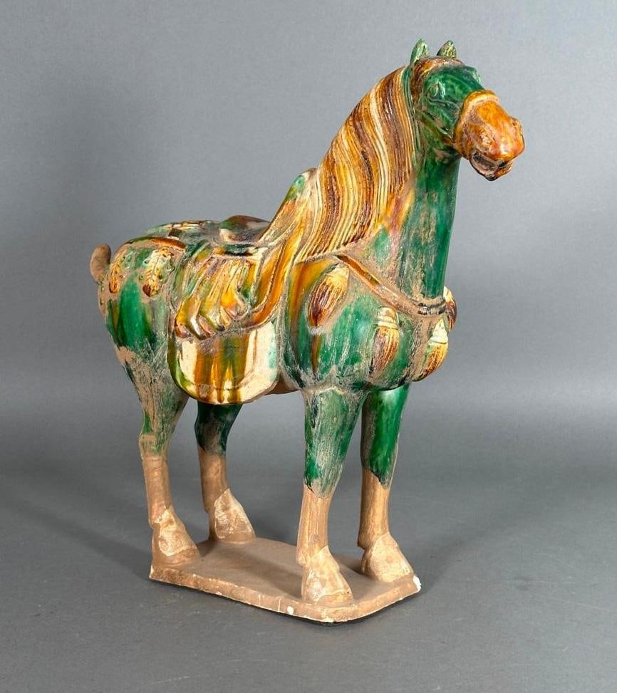 Chinese Tang Dynasty Style Pottery Figure of a Horse: Chinese Tang Dynasty Style Pottery Figure of a Horse, standing horse in Sancai glaze in amber, green and cream, on rectangular base. Dimensions: 14.75 x 13 x 5 in. Condition: Very good.