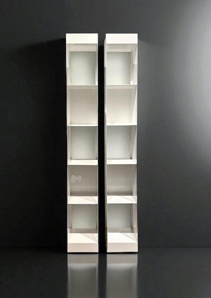 Two Modern Metal Bookshelves: Two Modern Metal Bookshelves, tall rectangular forms in white powder coated metal, with 5 shelves, each with one closed back. Dimensions: 71 x 10 x 10 in. Condition: One shelf with paint chip to front