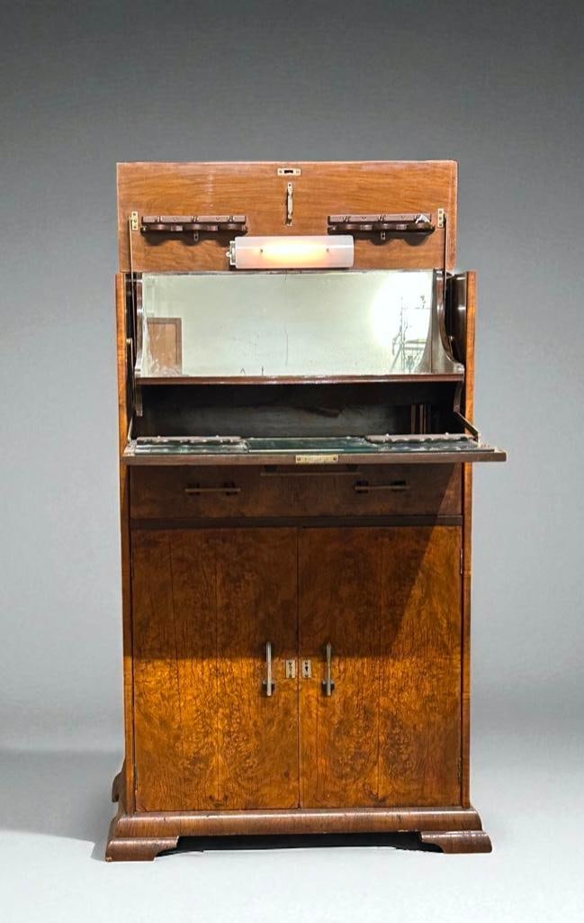 Art Deco Liquor Cabinet, 1930's: Burl wool case with drop down front, pull out surface and lower compartments. Interio light with mirrored back. Great form and function. Provenance: Collection of Sam Botero and Emery Von Sztankoczy.