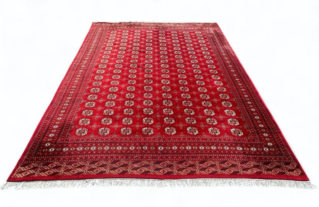 Pakistan Wool Bokhara Carpet, 12'6 x 14'6: Pakistan Wool Bokhara Carpet, typical design with regularly placed gul shapes in tan and cream on a red field. Dimensions: 12'6 x 14'6 Condition: Overall very good with expected wear from normal use.