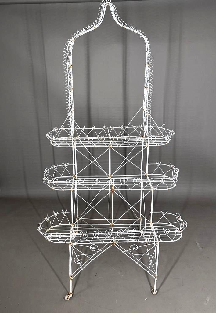 Victorian Style Wirework Three Tier Plant Stand: Victorian Style Wirework Three Tier Plant Stand, with gothic arch top and scrolled wirework over three graduated plant shelves, on a squared base and casters. Dimensions: 75 in. h.x 39 in. w. x 27