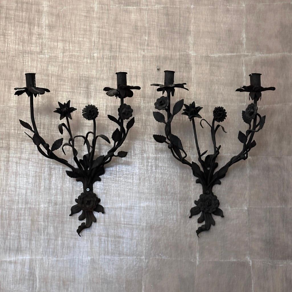 Pair of Tole Peinte Two Light Floral Wall Sconces: Pair of Tole Peinte Two Light Floral Wall Sconces, black painted tole, with two arms entwined with leaves and buds centering stems with blossoms, with a rose head back plate. Provenance: Charles Phill