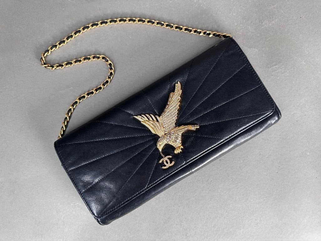 Authenticated Rare Chanel Eagle Bag: Debuted in 2001, the Eagle Bag; a black lambskin, quilted radiant flap, gold tone hardware of flying Eagle holding the CC logo, embellished with crystals. Gold tone metal and leather removable braided