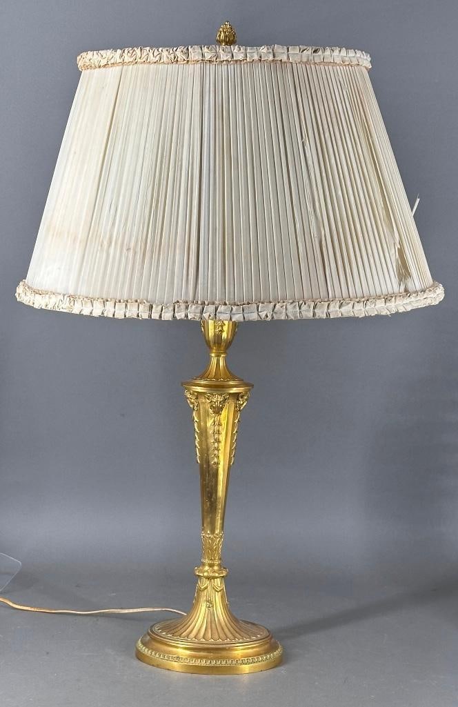 Gagneau et Cie, Paris, Neo-Classical Gilt Bronze Table Lamp, ca. 1900: Gadrooned oval shaped base with acanthus leaves and swags at knop, supporting a fluted oval shaped stem adorned with Ram's heads holding bell flowers, supporting an urn with bows and more flowers,