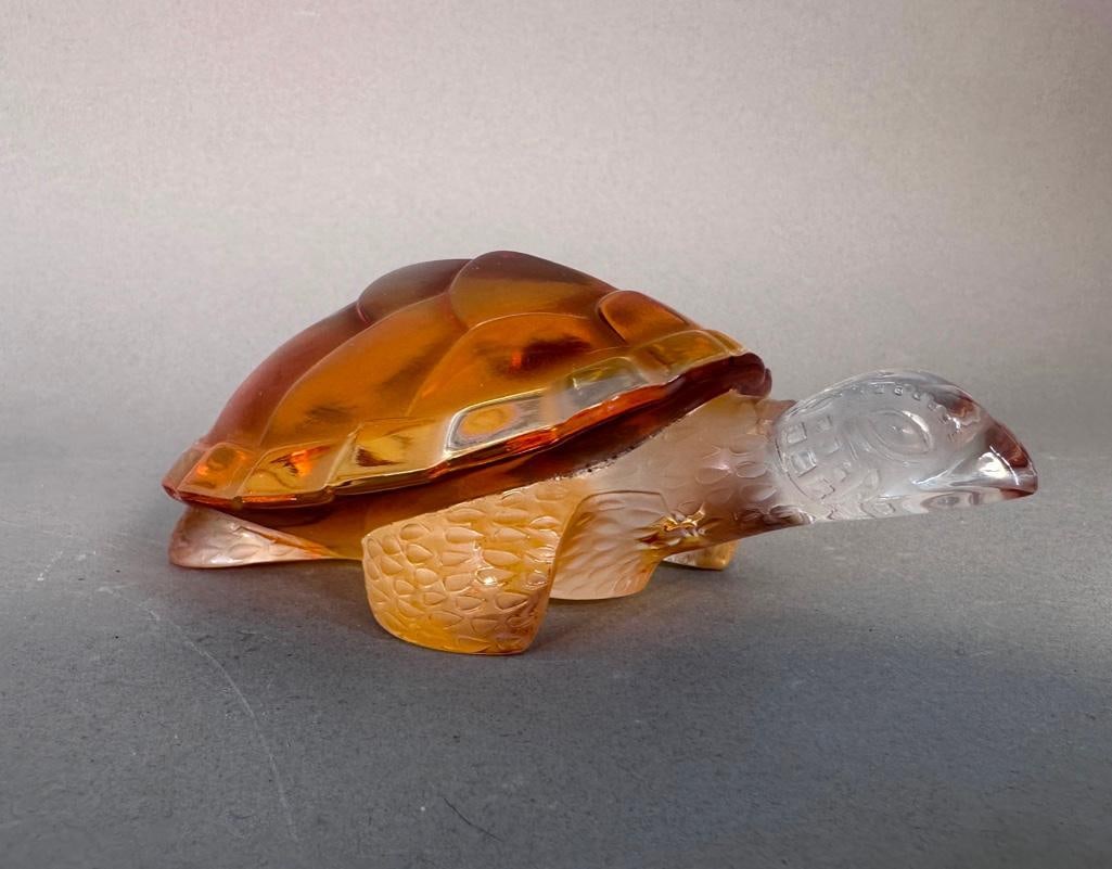 Lalique Crystal Caroline Turtle: Crystal turtle from Lalique titled "Caroline". Amber glass shell, head and limbs are made of clear glass. Measures apprx. 6 x 3.5 x 2.25"". Signed "Lalique France" on the under