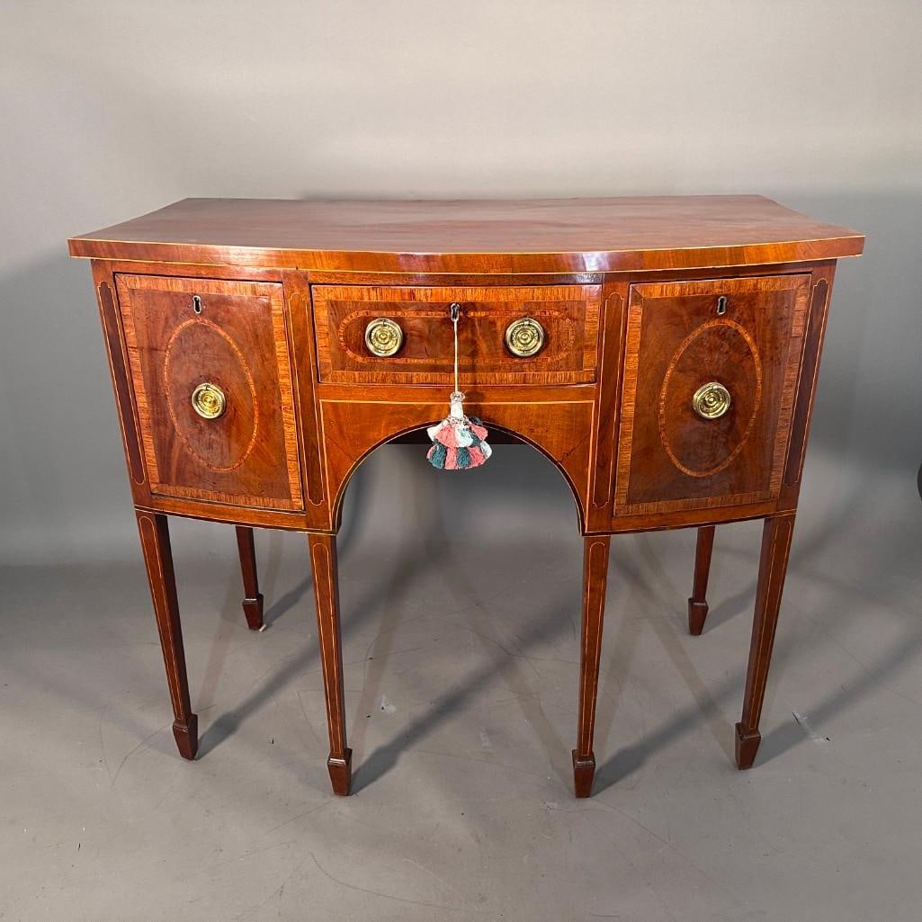 George III Mahogany Diminutive Sideboard, c.1790: George III Mahogany Diminutive Sideboard, c.1790. Bowfront form with satinwood banded borders, with a short drawer and two bottle drawers flanking, each with crossbanded borders and oval reserves, rai