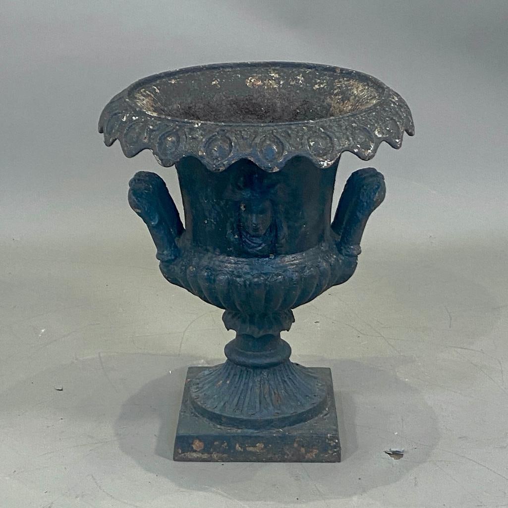 Victorian Cast Iron Painted Garden Urn: Victorian Cast Iron Painted Garden Urn, campana urn form with loop handles, cast to the front and back with female masks, on pedestal foot ans squared base. Dimensions: 19 in.h. x 16 in. dia.