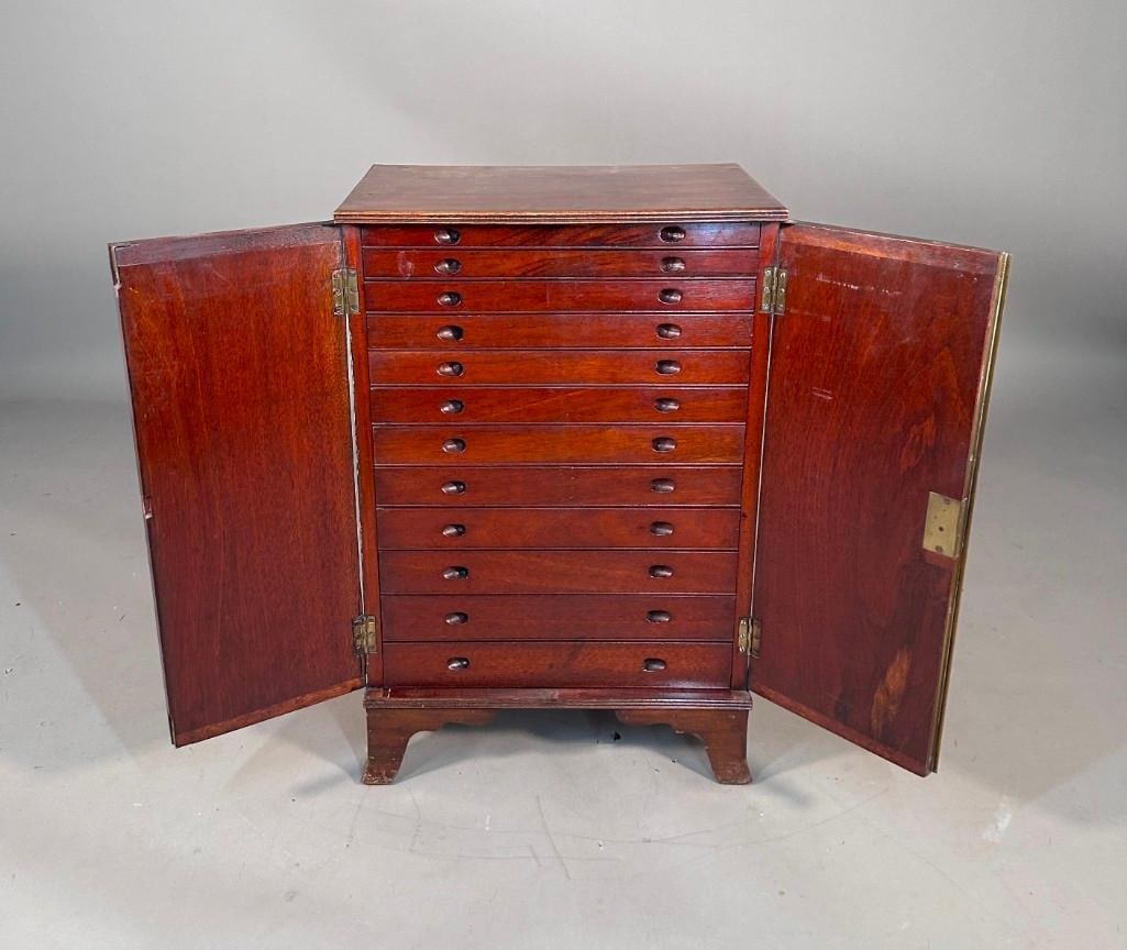 English Georgian Mahogany Collector's Cabinet, 18thc.: English Georgian Mahogany Collector's Cabinet, 18thc. The rectangular top with molded edge over a pair of hinged blind doors with brass molding, opening to 12 graduated long drawers with recessed 