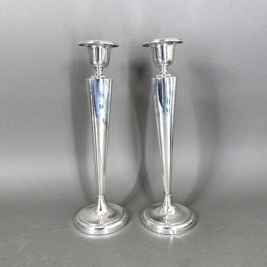 A Pair of Weighted Sterling Silver Candlesticks: A Pair of Weighted Sterling Silver Candlesticks, tapering squared forms with urn form capitals, on circular feet. Dimensions: 12 in.h. Condition: Both with dents to foot, and scattered dents overall.