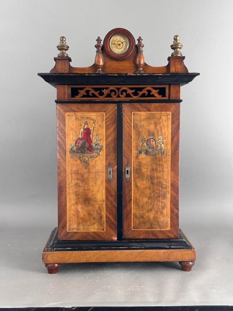 Britannia Swiss Smoking Cabinet Disc Musical Box, late 19thc.: Britannia Swiss Smoking Cabinet Disc Musical Box, late 19thc. Standing Cabinet form case with molded pediment with turned cornice enclosing a clock, over a pair of hinged inlaid wood doors applied wit
