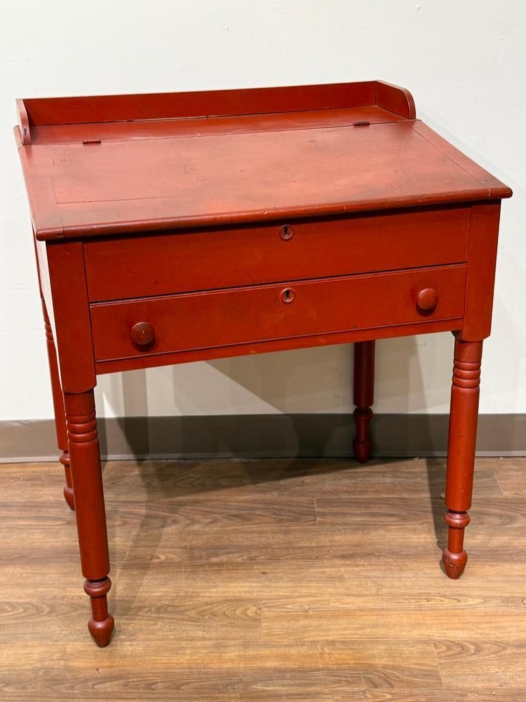 Antique Red Painted Slant Front Student Desk: Pine construction, overall painted red, hinged listing front slant with storage, above single drawer with lock (no key), turned legs, small gallery on top, apprx 36 x 31 x 22.5 in. Condition: wood fis
