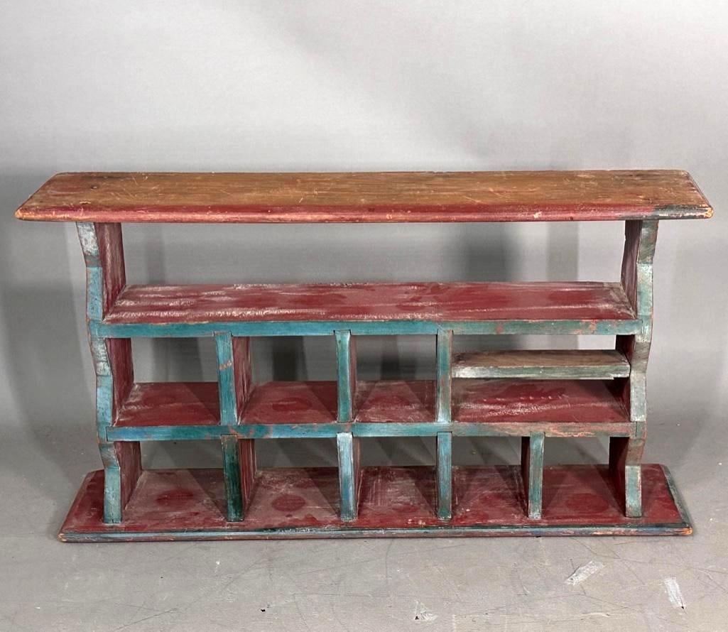 Antique Pine Cubby Shelf: Constructed of pine with red and blue paint, worn in areas, having many small interior shelves for display of crocks or small items on tabletop. Apprx 20.5"H x 38"L x 8.5"D. Condition: