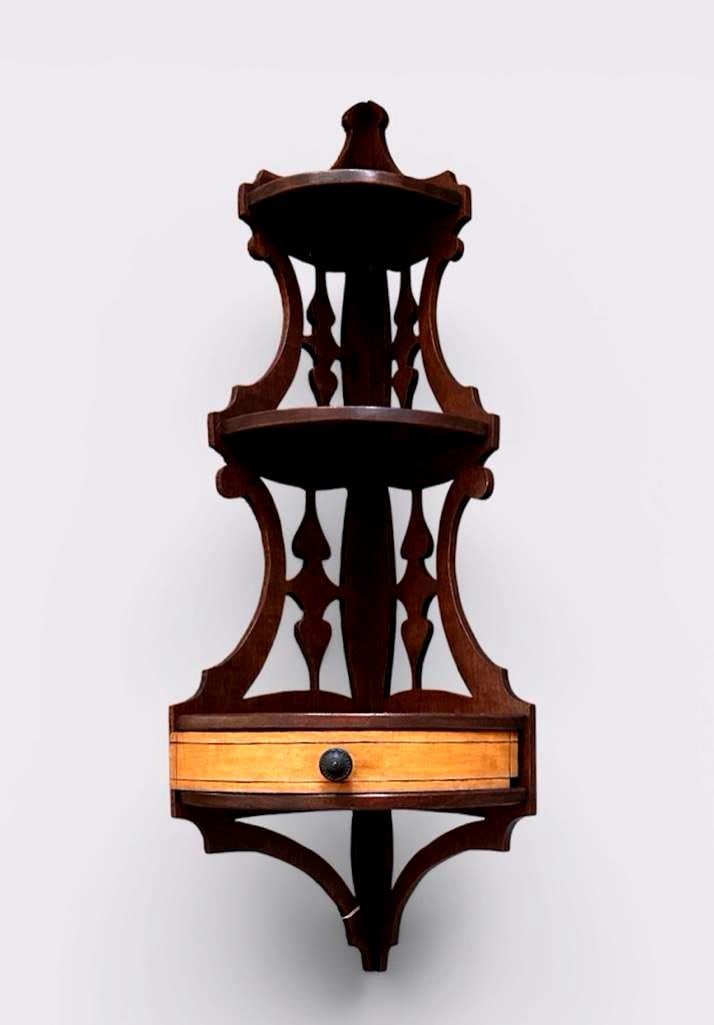 Mahogany Corner Shelf: Carved open work corner shelf with three shelves, curved front, upper corner drilled for wall attachment, apprx 32.5"H x 12"W x 12"D. Condition: White paint splotches on verso. Drilled for