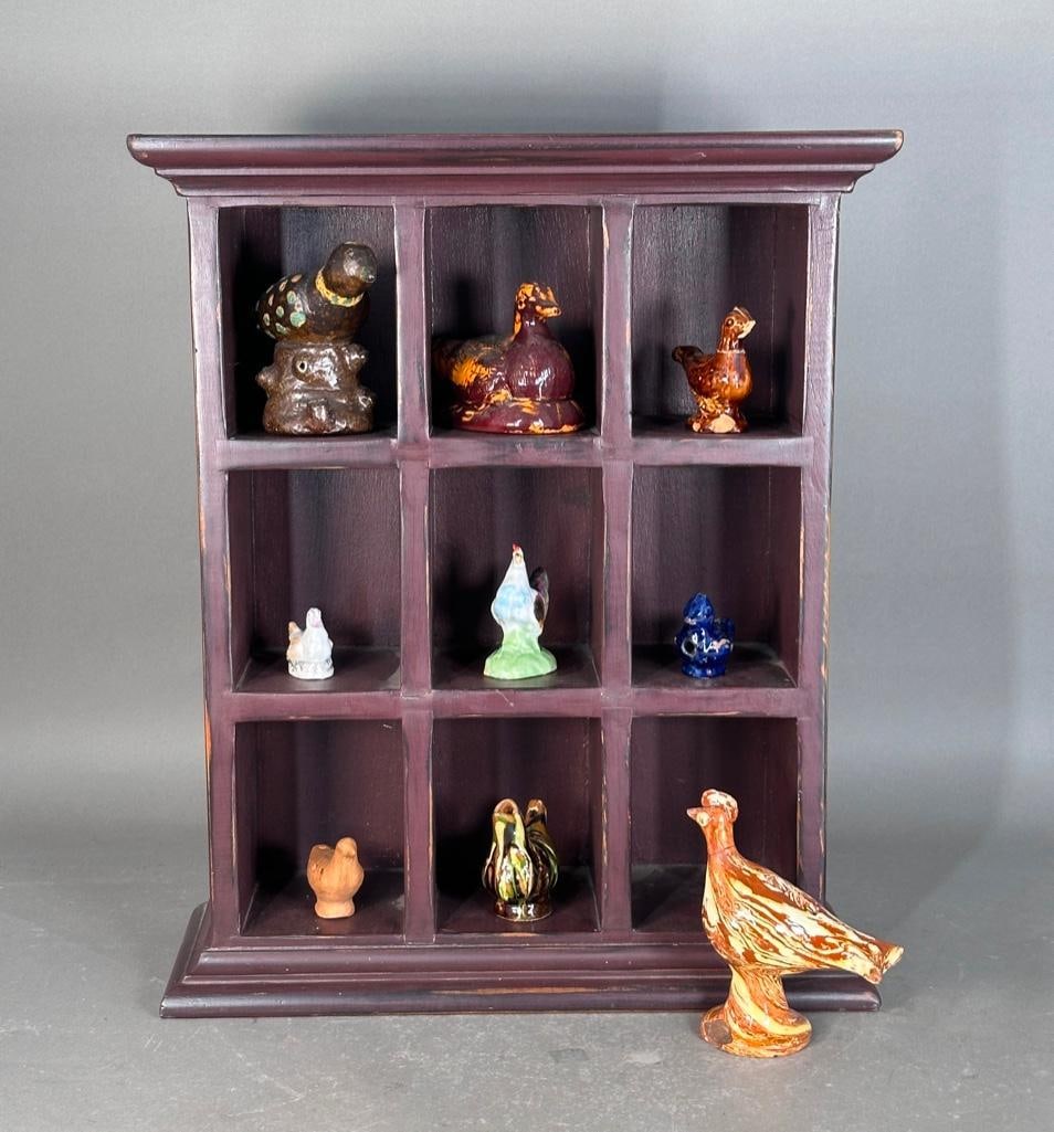 Wood Curiosity Display Cabinet with Collection of Bird Whistles and Figures: Petite wood display cabinet with nine cubicles, painted a warm brown color, apprx 21.25"H x 17.25"W x 6.75"D. Lot includes nine birds, molded in ceramic, red clay, stoneware, all glazed ex