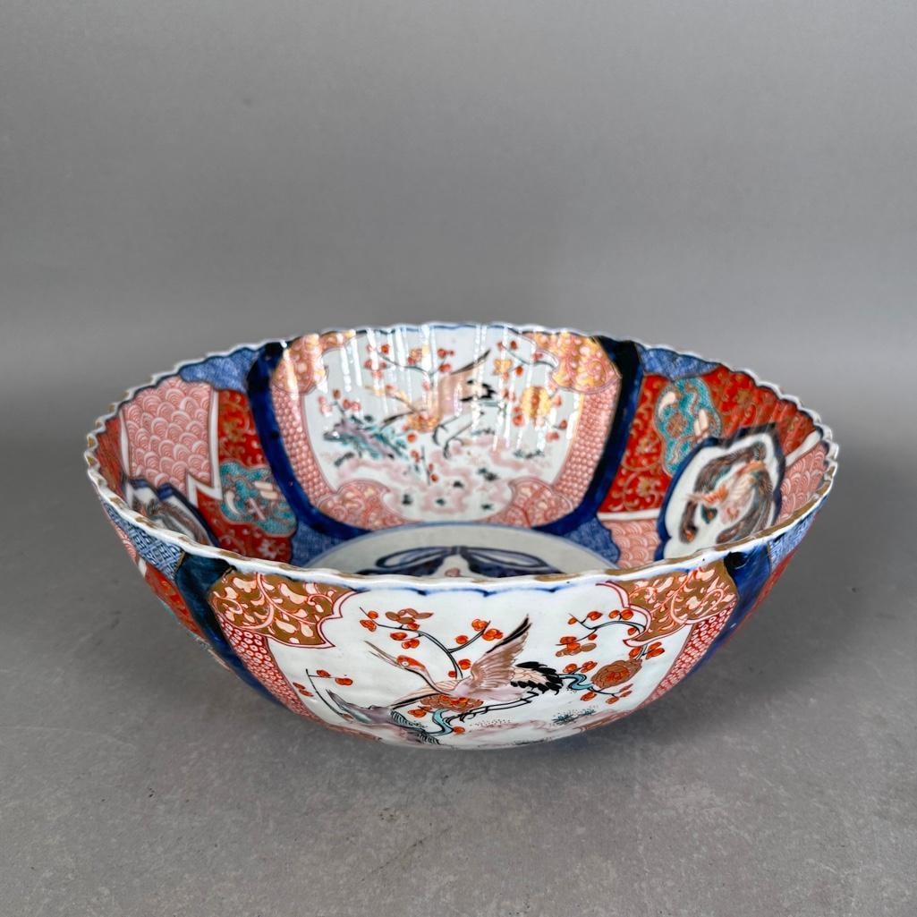 Japanese Imari Punch Bowl, 19th Century: Porcelain bowl, fluted sides and scalloped edge; under-glaze blue painted decoration with hand painted enamels and gilt accents. Large panels with plumed birds and cranes on diapered backgrounds with