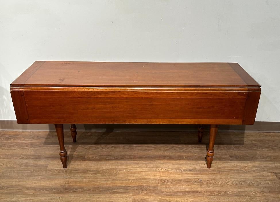 Cherry Drop-leaf Harvest Table, 20th Century: Solid cherry wood table on turned legs, with wood butterfly joints and wood post construction. Drop leaf sides with retractable supports underneath. turned spindle legs, warm brown finish, 29"H x