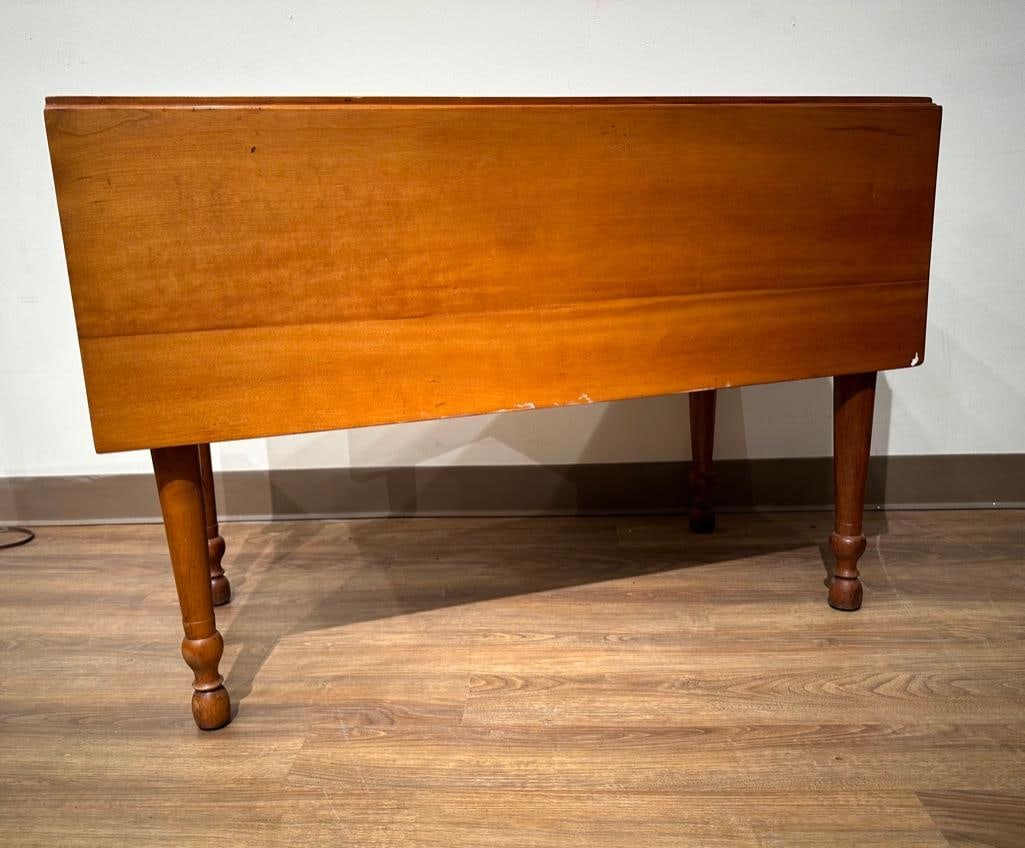 Antique Maple Drop Leaf Table: Table with two drop leaves, turned legs, warm honey color, with two swing supports for leaves for a squared table; 29"H x 47" x 43" open, 20.5" leaves down. Condition: old scuffs on