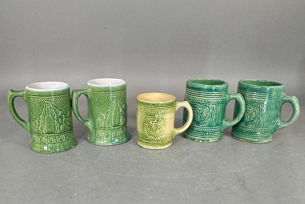 Five Old Heidelberg Green Glazed Mugs: Pottery mugs with handles, in green glazed, with molded design, each apprx 5.25"H, one smaller one is 4.25"H. Condition: light wear from use.