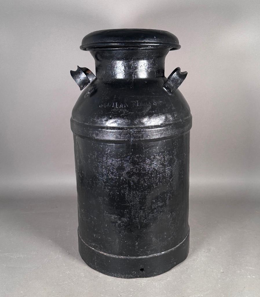 19th Century American Follensbee Milk Can: Five gallon metal milk can, painted black, two handles stamped 'FOLLENSBEE', the lid also stamped with the farm name of 'SCOTLAN FARMS'. Dimensions: Apprx 2'H x 1'D. Condition: