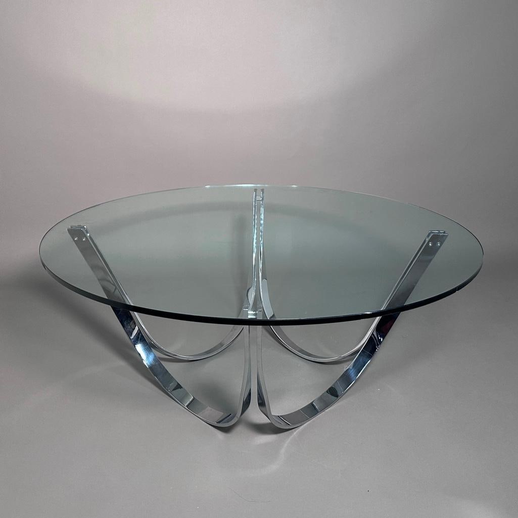 Roger Sprunger for Dunbar, Crome and Glass Round Coffee Table: Coffee Table in chromed and twisted steel blades, ca. 1970's. Round thick glass shelf, all forming a stable whole. Apprx 18"H x 39"D round. Roger Sprunger (1920–2008) was a prominent American Mid-Ce