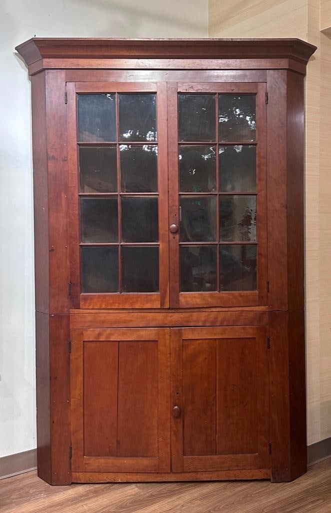 19th Century American Corner Cupboard: Pine corner cupboard with two glass and mullion doors on upper section, having three interior shelves; the lower compartment has two hinged doors and one shelf, the base may have been raised on feet w