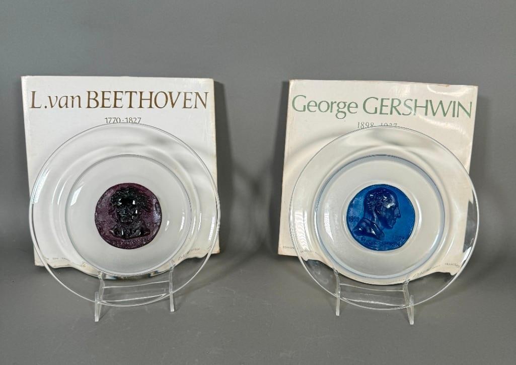 Two Daum Portrait Pate de Verre Plates, Gershwin and Beethoven: From the Edition Des Grands Musiciens, made in France. Both clear glass plates with color center with lost wax portrait of the musicians. Apprx 9.75"W each, with original boxes. Condition: very good.