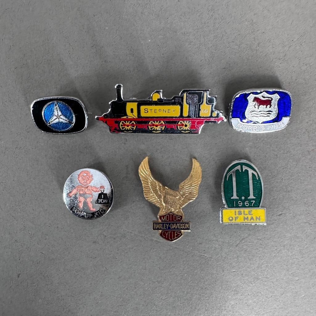 A Collection of Vintage British Badges: Six British badges, or pins, the largest being the Stepney train measuring 1.75"W. Besides the Stepney, lot includes a Harley Davidson Eagle, Mercedes Benz, Morris Mini, Ton-Up Kid and T.T. 1967 Isle 