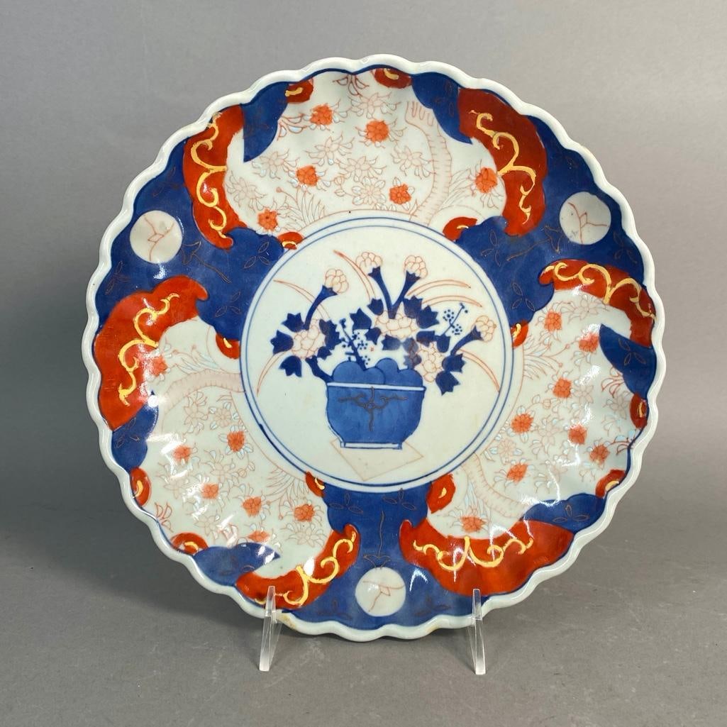 Japanese Style Imari Plate: Chinese plate in the Japanese taste, 20th century. Scalloped edge and hand painted with a central vase of flowers in red, blue and white colors. Auspicious four character Chinese mark on bottom. Apprx
