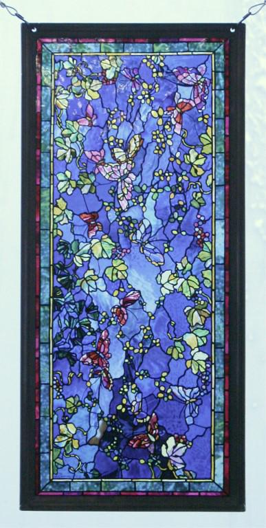John La Farge Reproduction "Butterflies & Foliage": This beautiful piece radiates blue with multicolored leaves, flowers, & butterflies inside a grey metal frame. This reproduction showcases intricate details, and stunning color that appears to be pain