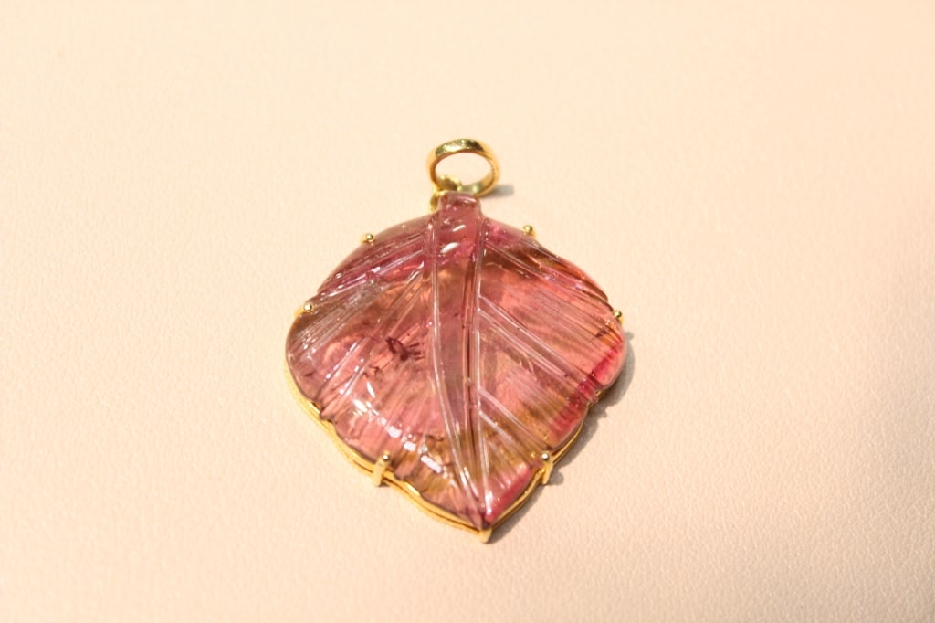 Carved Tourmaline Leaf Pendant set in Yellow Gold: Dimension: 4cm x3 cm. a natural tourmaline gemstone that has been expertly hand-carved into a detailed leaf shape. The carving includes delicate grooves on the surface to emulate the veins of a real l