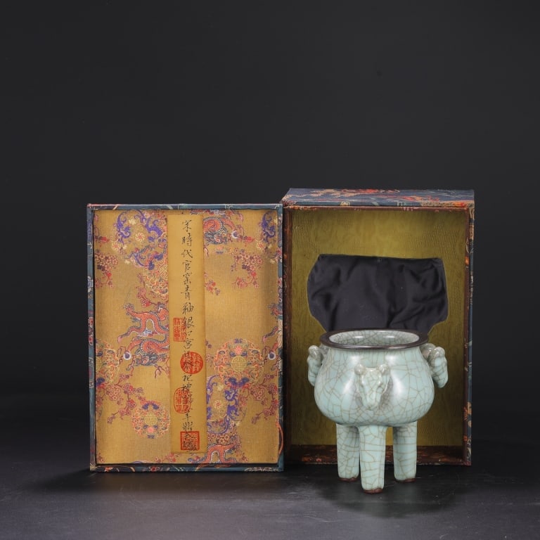 Chinese celadon crackle-glazed tripod censer: Dimension: 18.5cm H x16.5cm W. The censer has a compressed, globular body supported by three tall, tapering legs. It features two small, upright handles on the rim. This specific shape with