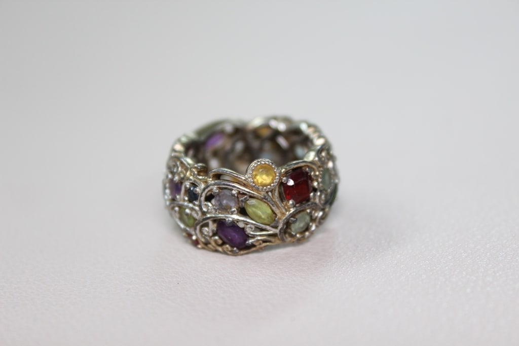 "Mini-Carnival" Multi-gemstone Eternity Ring: The ring features an array of colorful, oval-shaped semi-precious gemstones set in a vibrant "rainbow" style. Michael Valitutti style.