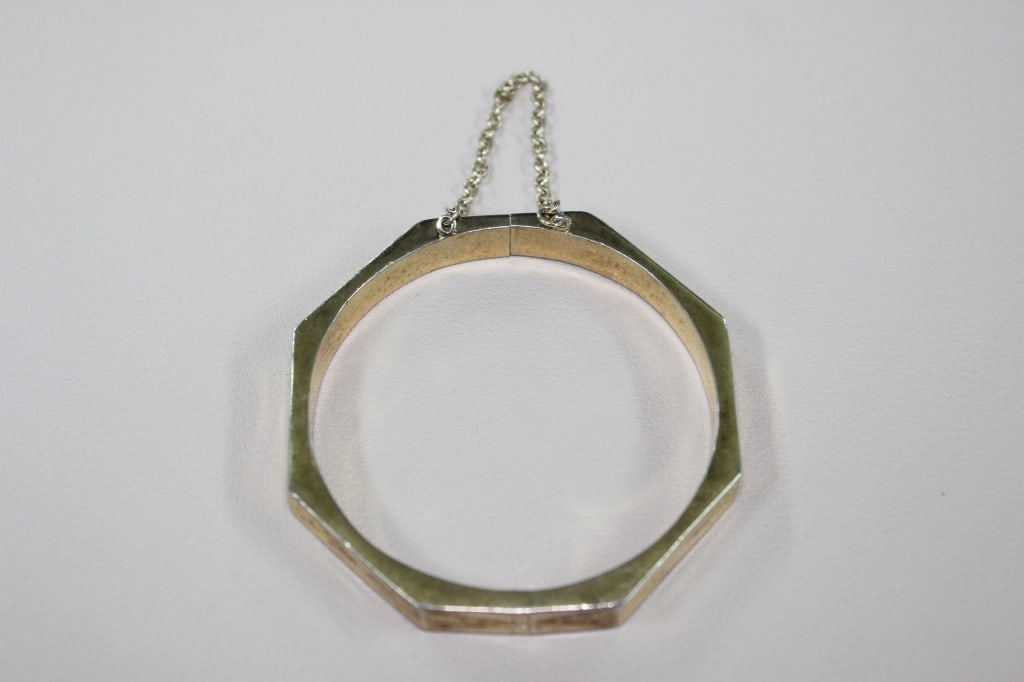 Vintage Octagonal Hinged Bangle Bracelet: Dimension:2 3/4"W.The bracelet has an eight-sided, geometric shape, distinguishing it from traditional round bangles. Each facet appears to have simple, subtle etched or engraved lines for added detai