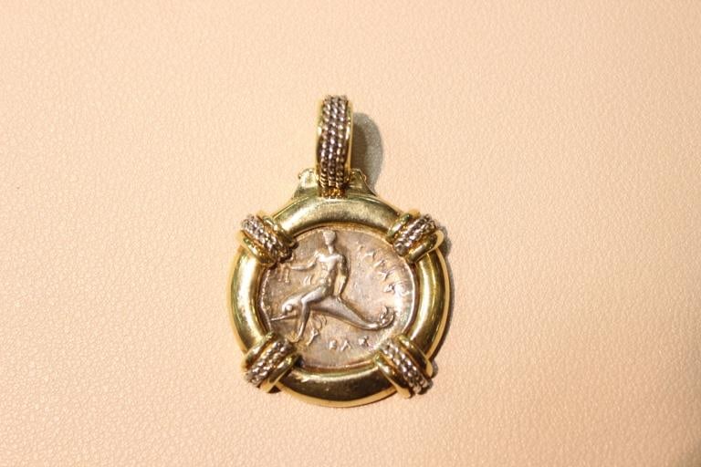 Ancient Greek “Boy on Dolphin“ Nomos Coin Set in a 18k gold bezel.: Ancient Greek "Boy on a Dolphin" silver coin, also known as a Nomos or Didrachm, set in a 18k gold bezel.Dimension: 24.15gram. 4cm x3cm.The coin depicts Taras, the son of the Greek sea god Poseidon. A