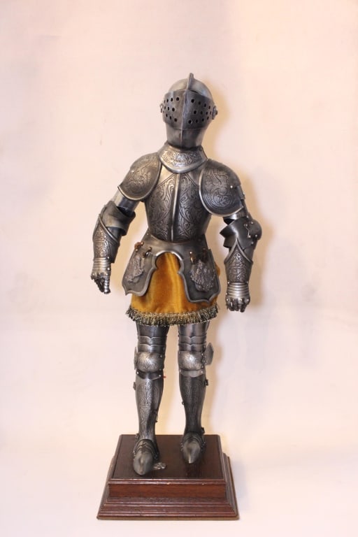European Renaissance-style Suit of Knightly Armor: Dimension:25"H decorative Renaissance-style suit of armor, mounted on a wooden stand. The armor is etched with elaborate floral designs and heraldic motifs, including a double-headed eagle emblem.