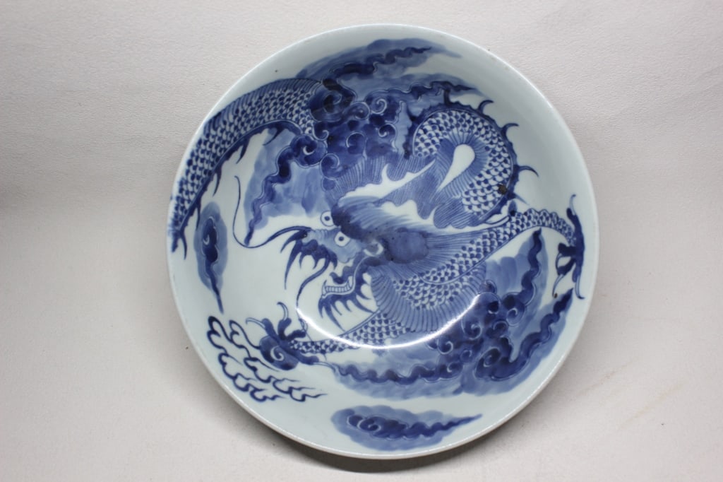 Chinese blue and white porcelain dragon Bowl: The bowl features a ferocious five-clawed dragon—traditionally a symbol of the Emperor's divine authority and imperial power. Dimension: 8"W. The dragon is typically shown writhing amidst