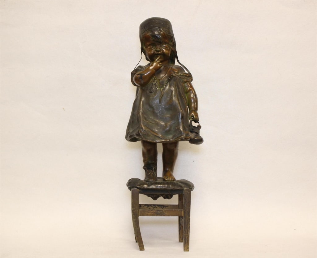 Bronze Sculpture of a Shy Young Girl ,Juan Clara: Dimension: 12"H. The piece depicts a shy young girl wearing a bonnet and a simple dress, standing on a cushioned stool or chair. She has one finger pressed to her lips in a "hush" gesture while