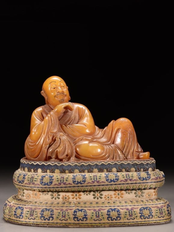 Chinese Shoushan stone carving of a Luohan: Dimension: 7.5cm H x 10.3 x 5.5cm,weight is 318gram. The Luohan is depicted reclining, a style characterized by voluminous, flowing robes often incised with delicate floral patterns or "cloud"