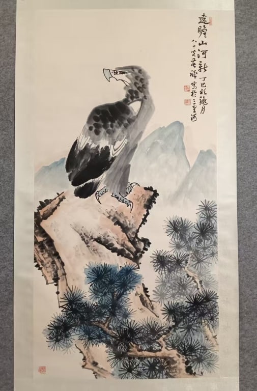Chinese Ink Color Hanging Scroll,Signed: titled "Looking at the Majestic Mountains and Rivers from Afar". The artwork depicts a majestic eagle perched atop a rugged cliff, set against a backdrop of towering mountains and lush pine trees.