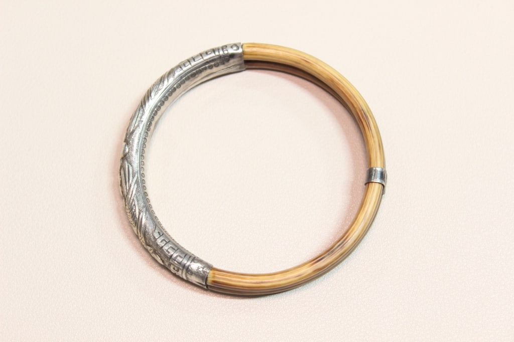 Vintage Chinese Sterling silver and Rattan Bangle: The main circular part of the bangle is made of rattan . The metalwork is typically sterling silver. The silver sections feature intricate repoussé or etched designs, which often depict 