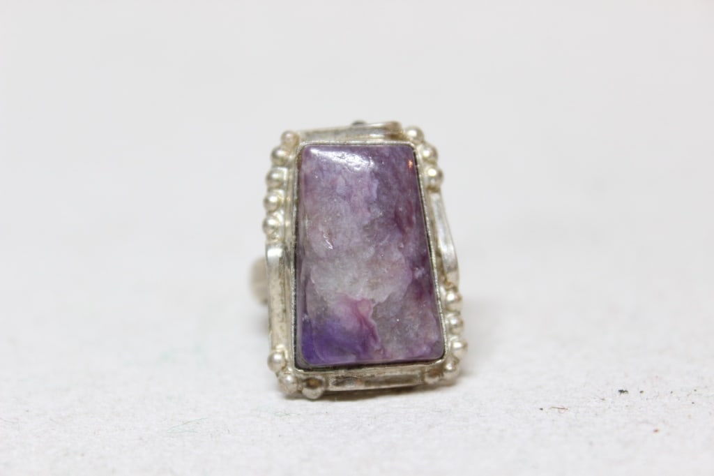 Vintage Charoite gemstone Silver Ring: Charoite: Known for its distinct swirling, chatoyant (shimmering) patterns of lavender, violet, and purple. It is found exclusively in Siberia, Russia.The stone is held in a bezel setting with a decor