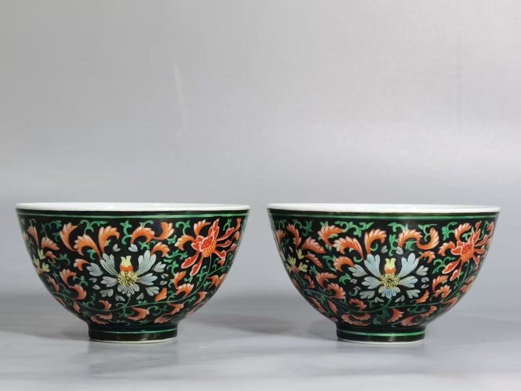 Pair Chinese black-ground Porcelain Bowls,Mark: Dimension : 7cm w x 5cm H . The exterior body of each bowl is covered in a deep black enamel ground. This background contrasts sharply with the vibrant blossoms, a decorative style historically known