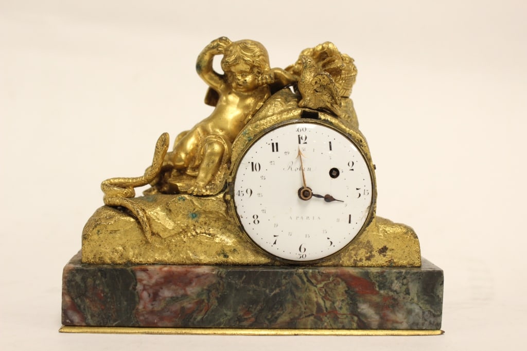 French Gilt-bronze (ormolu) Mantel Clock: Dimension : 5"x 2"x4" The clock features a finely cast gilt-bronze figure of a cherub (putto) leaning against the clock housing. Nearby elements include a snake slithering up the rockwork and a small