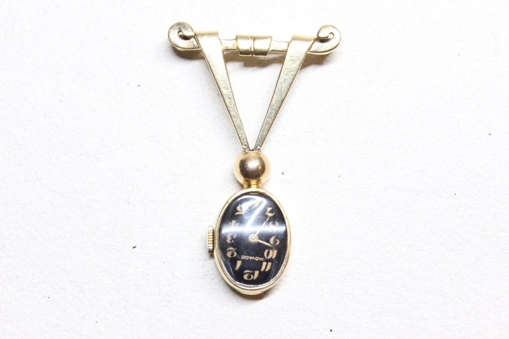 Vintage nurses' fob watch brooch: Dimension: The dial is marked Movado,It features a black enamel oval face with gold-tone Arabic numerals and a manual-wind movement, typical of high-quality mid-century nursing watches.